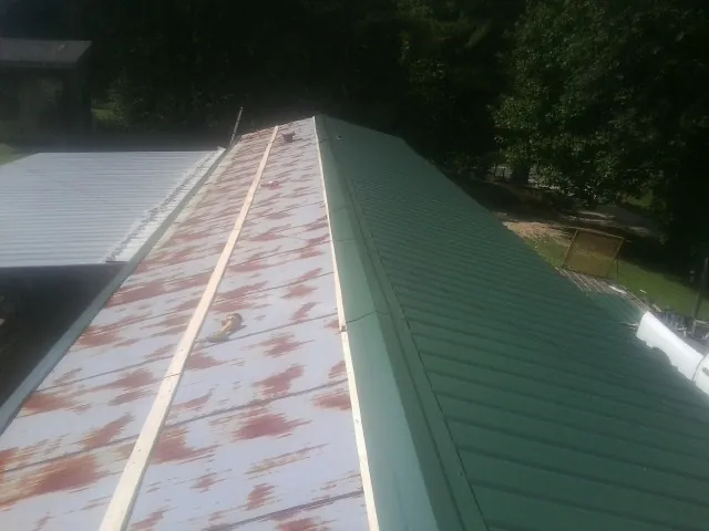 Old rusted panels beside newly installed green metal roofing — Wind Damage Roof Repair by Roofing Brothers in Lidgerwood