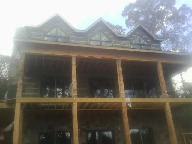 Dormers and porch framing on a large log home under construction — Roof Coating work by our crew in Lidgerwood