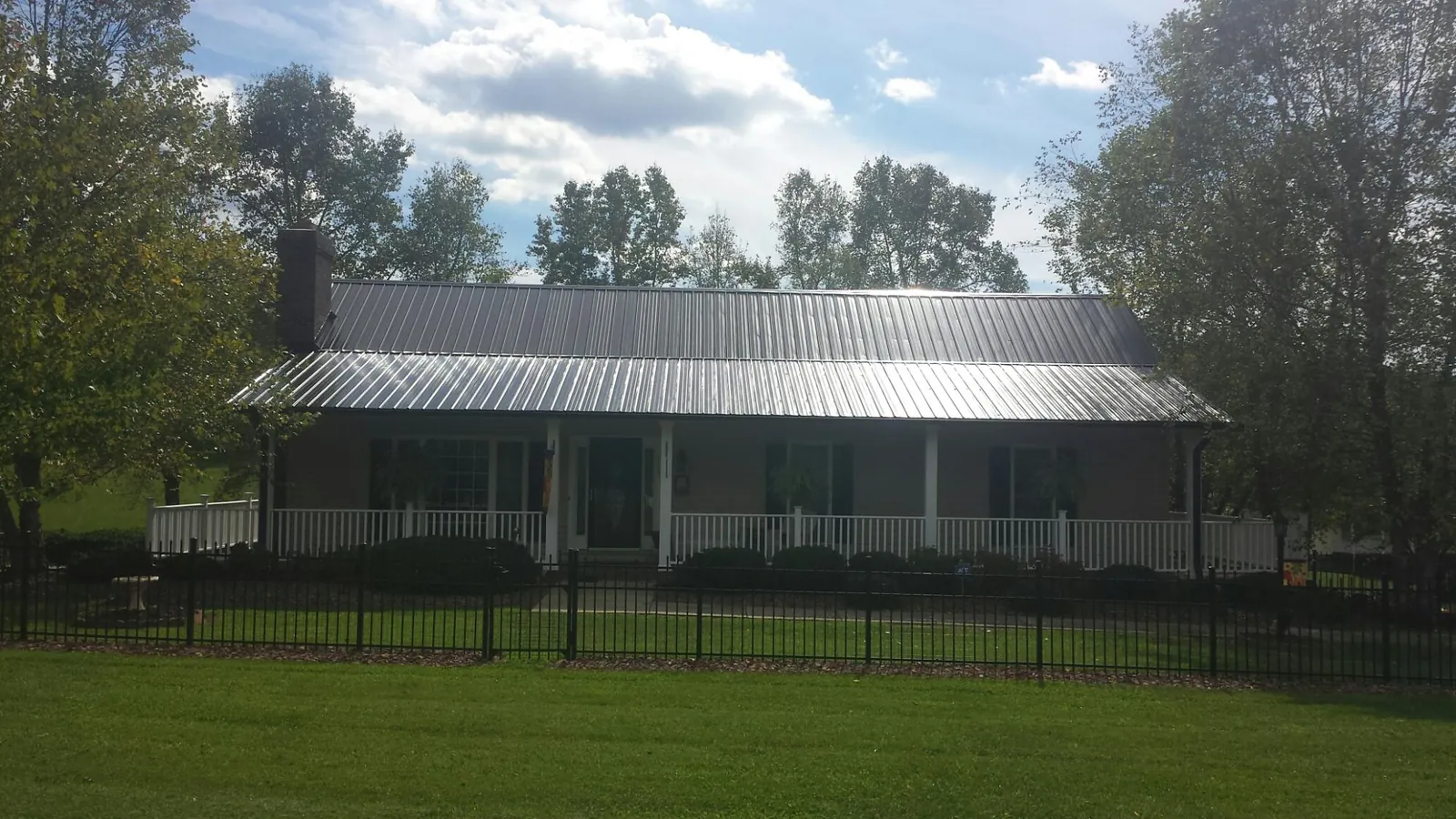 Gray metal roof on a brick ranch with a full width front porch — Gutter Guard Installation work by our crew in Lidgerwood