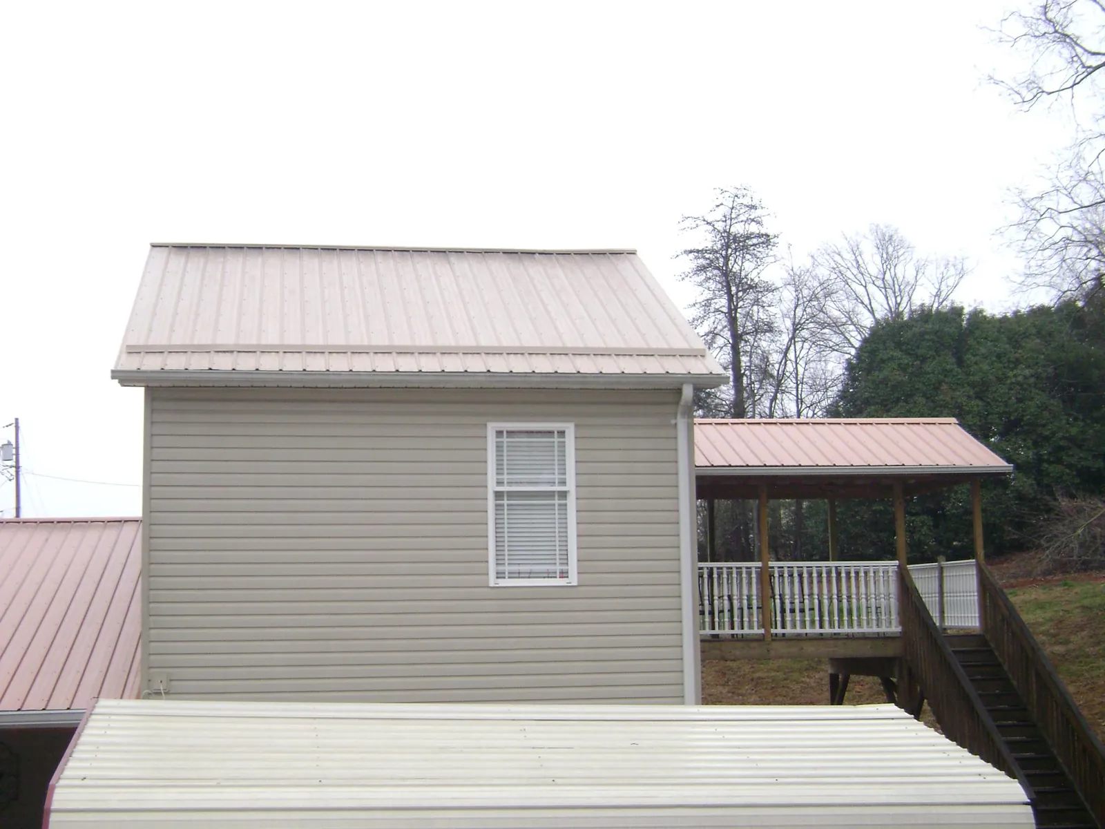 Tan metal roofs on a two story addition and attached porch, from a Roof Replacement job in Lidgerwood